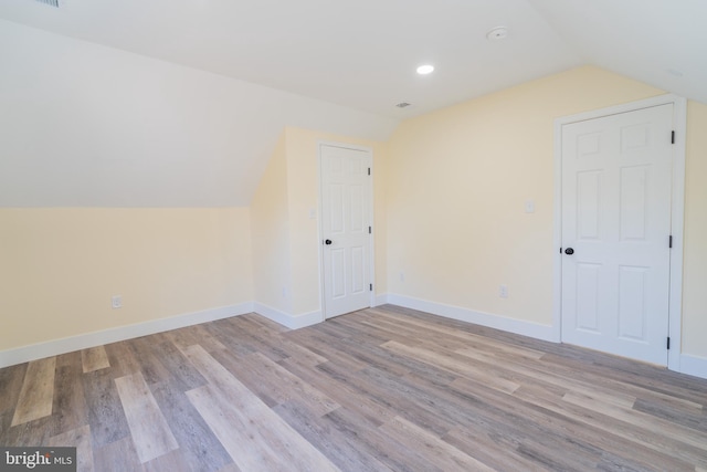 additional living space featuring light wood-type flooring and lofted ceiling