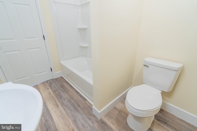 bathroom featuring hardwood / wood-style flooring, toilet, and tub / shower combination