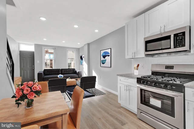 kitchen with white cabinets, stainless steel appliances, and light stone counters