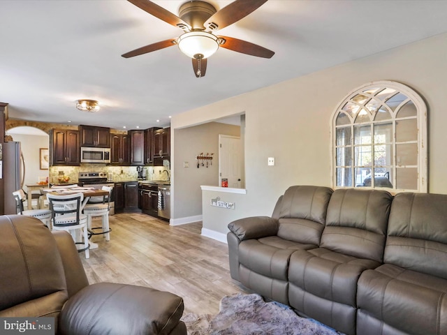 living room featuring light wood-type flooring, ceiling fan, and sink