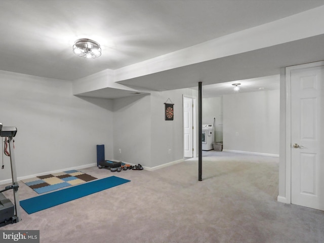 exercise room featuring washer / clothes dryer and light carpet