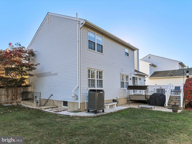 back of house with central air condition unit, a lawn, and a deck