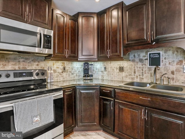 kitchen featuring stainless steel appliances, sink, backsplash, dark brown cabinets, and light wood-type flooring