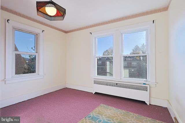 carpeted spare room featuring radiator heating unit