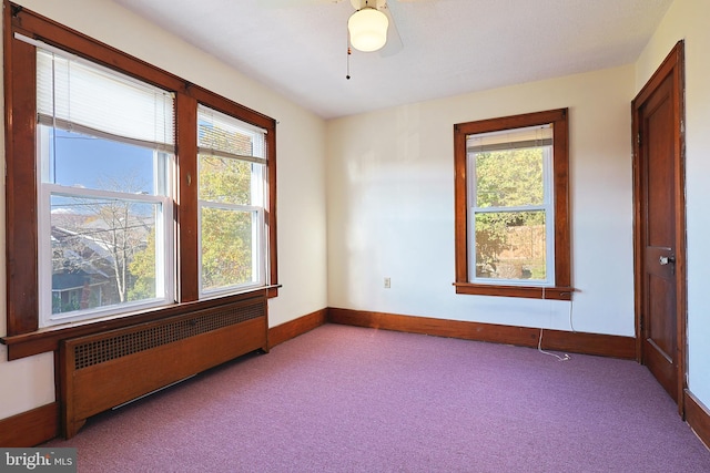 unfurnished room featuring light colored carpet, ceiling fan, and radiator