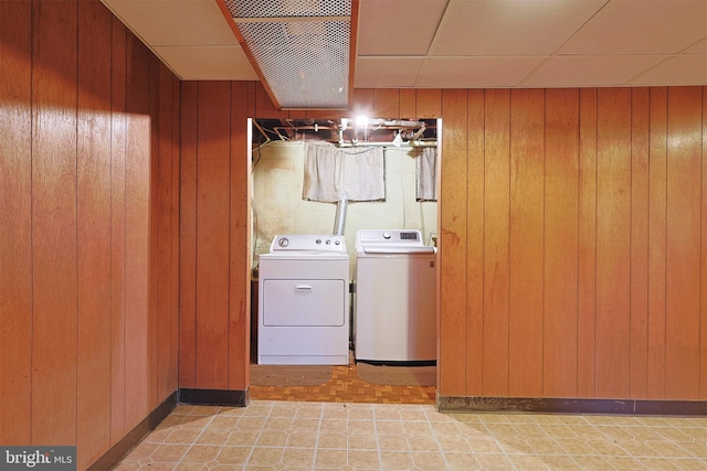 clothes washing area featuring washer and clothes dryer and wood walls