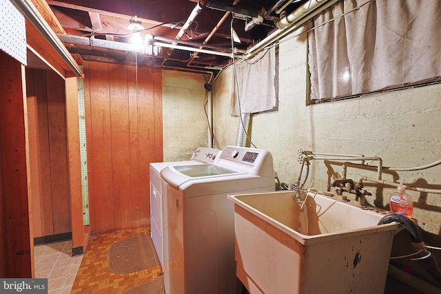 clothes washing area with wood walls, sink, and washing machine and clothes dryer