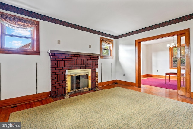 unfurnished living room featuring a fireplace, wood-type flooring, and a chandelier