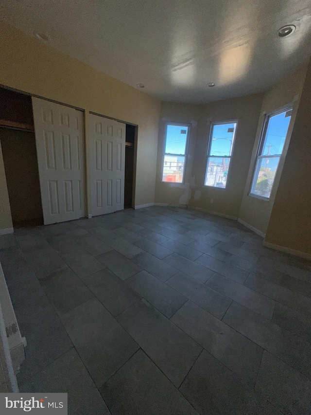 unfurnished bedroom with two closets and dark tile patterned flooring