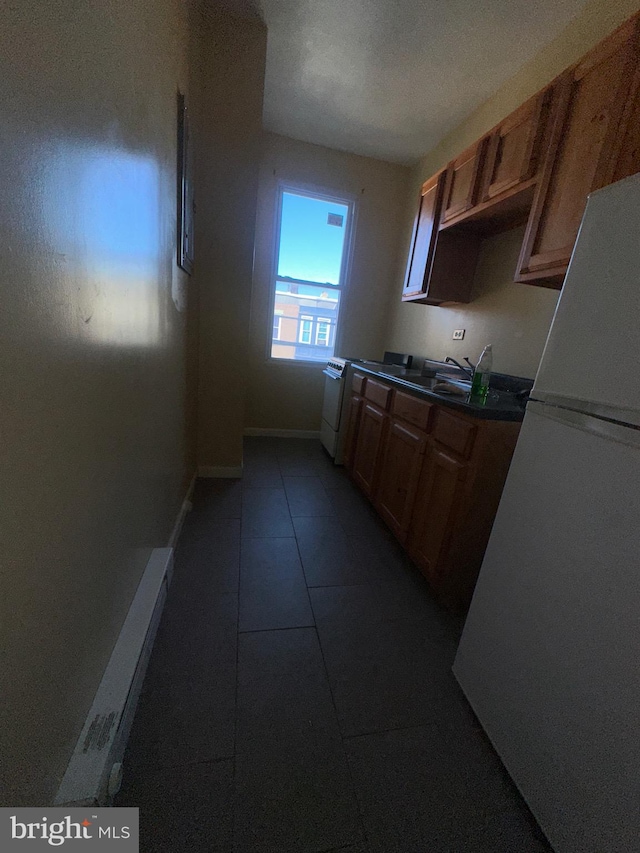 kitchen with sink, dark tile patterned flooring, and white refrigerator