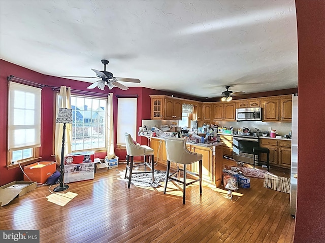 kitchen featuring appliances with stainless steel finishes, light wood-type flooring, ceiling fan, and backsplash