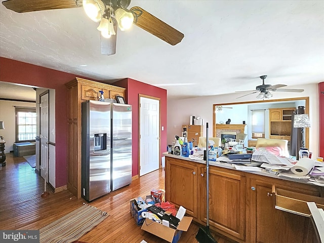 kitchen with stainless steel fridge with ice dispenser, dark hardwood / wood-style flooring, ceiling fan, and a brick fireplace