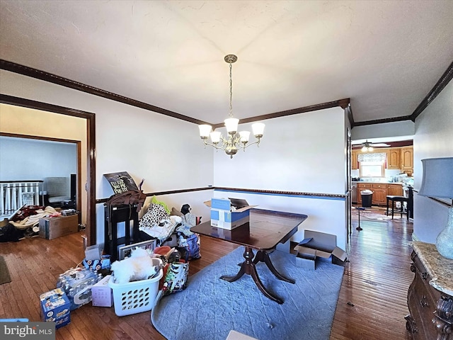 dining space with ceiling fan with notable chandelier, ornamental molding, and dark hardwood / wood-style flooring