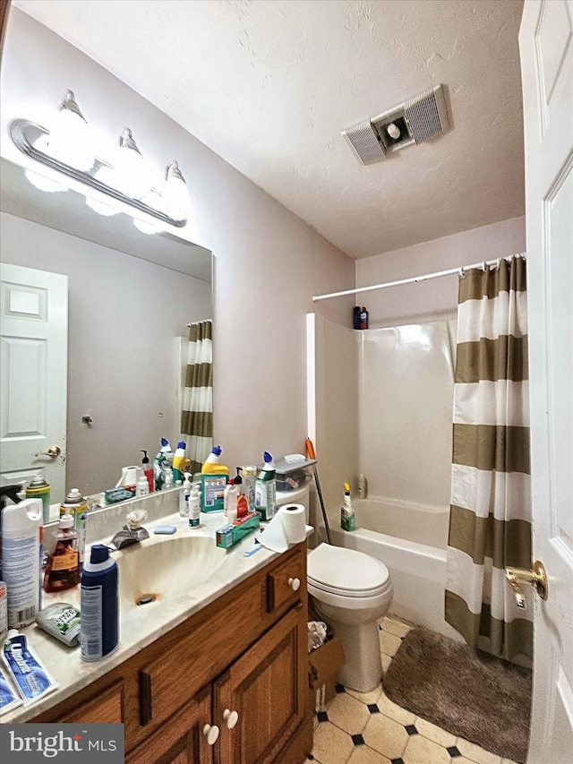 full bathroom with vanity, shower / tub combo, toilet, and a textured ceiling