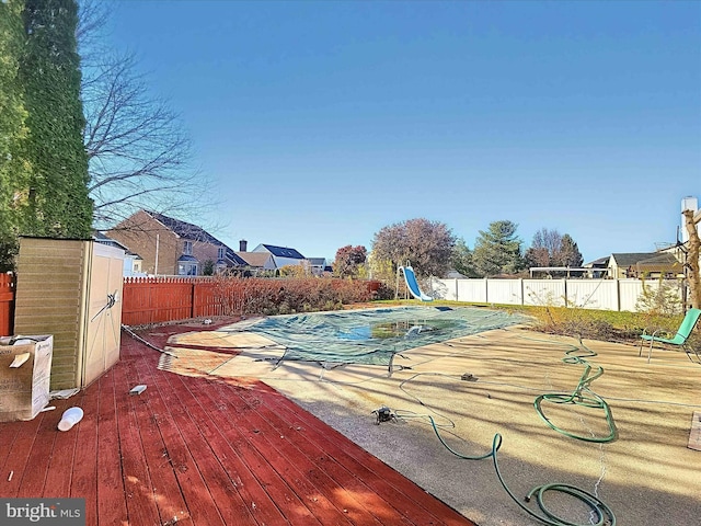 view of swimming pool with a wooden deck, a water slide, and a shed