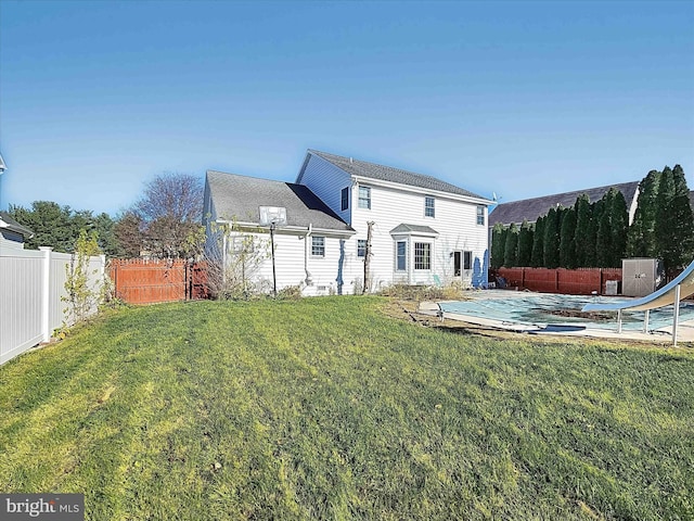 back of property featuring a trampoline and a yard