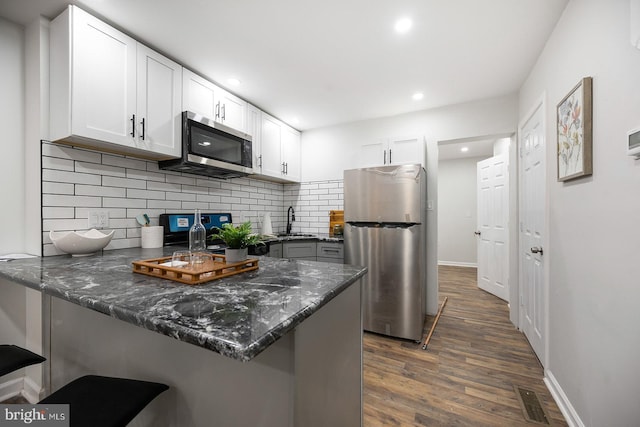 kitchen with white cabinetry, kitchen peninsula, dark hardwood / wood-style floors, and stainless steel appliances