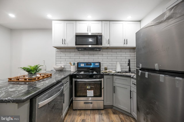 kitchen featuring stainless steel appliances, hardwood / wood-style flooring, sink, kitchen peninsula, and backsplash