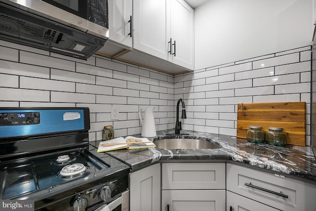 kitchen featuring white cabinets, black range oven, sink, and backsplash