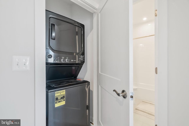 clothes washing area featuring tile patterned floors and stacked washer / dryer