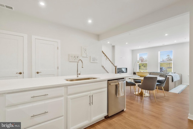 kitchen featuring light wood-type flooring, white cabinetry, stainless steel dishwasher, and sink