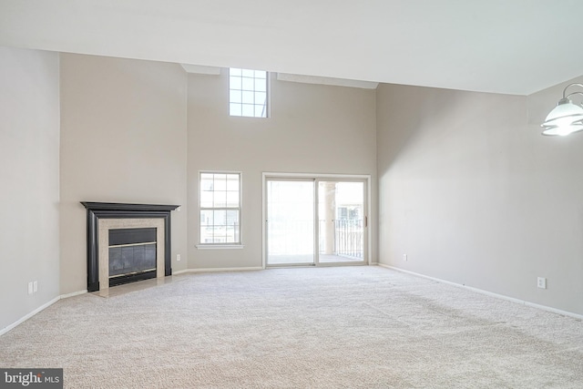 unfurnished living room with a high ceiling, light carpet, and a healthy amount of sunlight