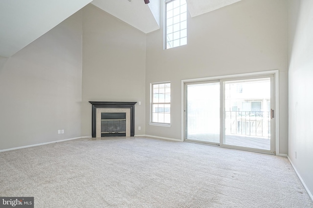 unfurnished living room with high vaulted ceiling, light carpet, and ceiling fan