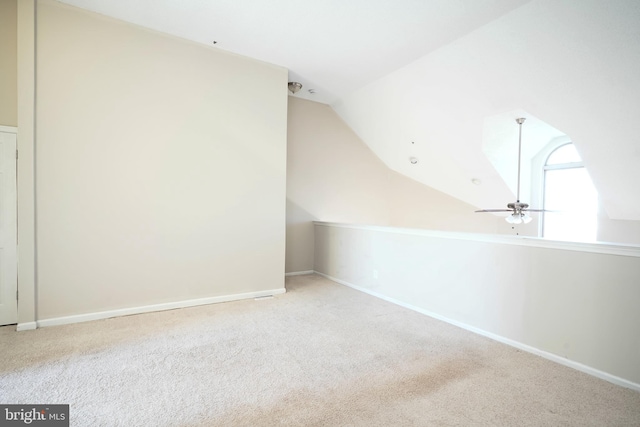 additional living space with light colored carpet, ceiling fan, and vaulted ceiling