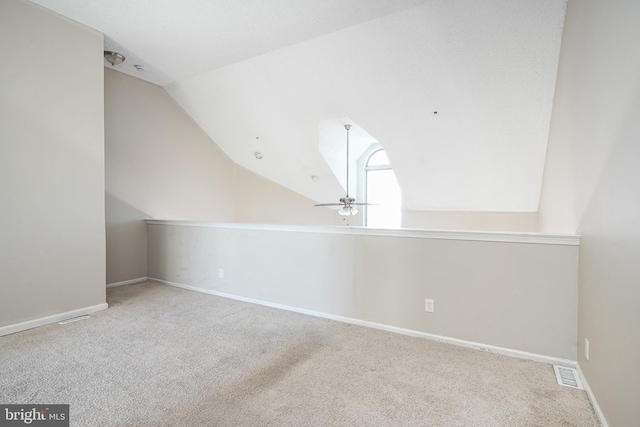 additional living space with vaulted ceiling, light colored carpet, and ceiling fan