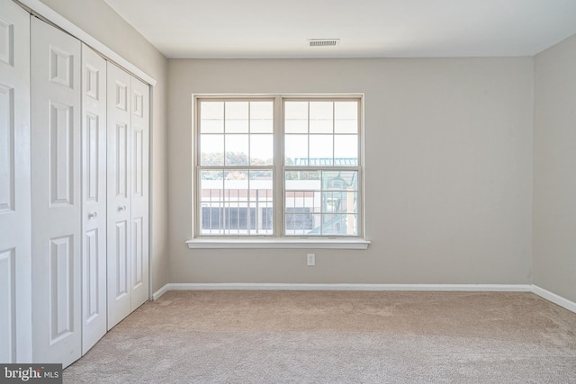 unfurnished bedroom with light carpet and a closet