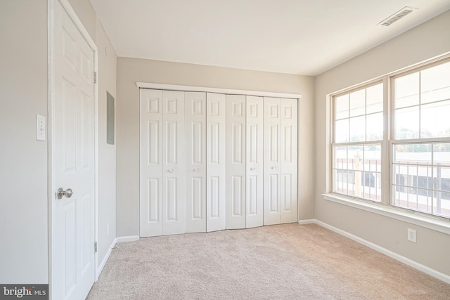 unfurnished bedroom featuring light carpet and a closet