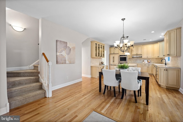 dining area featuring light hardwood / wood-style floors, sink, and an inviting chandelier