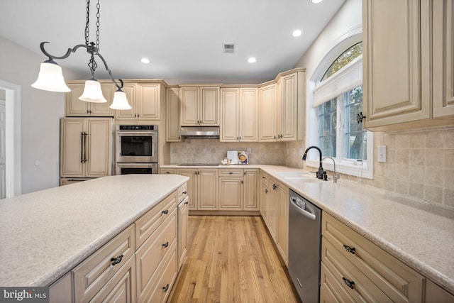 kitchen with stainless steel appliances, decorative backsplash, sink, pendant lighting, and light hardwood / wood-style flooring