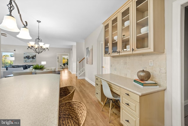 interior space with built in desk, a breakfast bar area, light wood-type flooring, backsplash, and pendant lighting