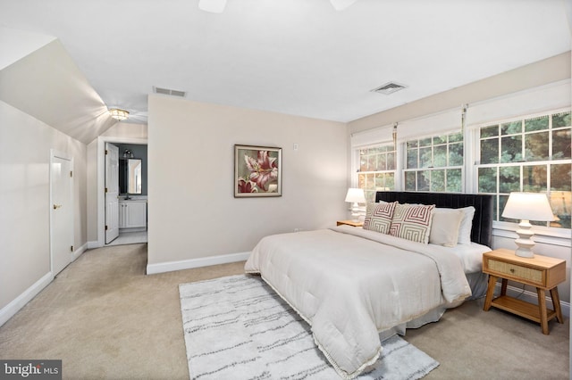 bedroom featuring ensuite bathroom, light carpet, and ceiling fan