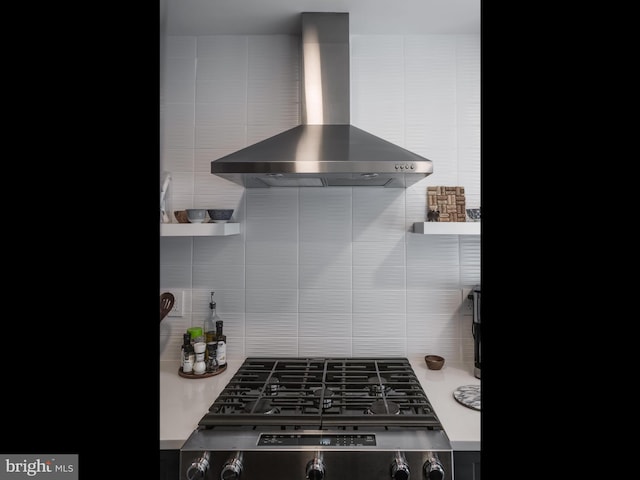 kitchen featuring backsplash, stainless steel stove, and wall chimney exhaust hood