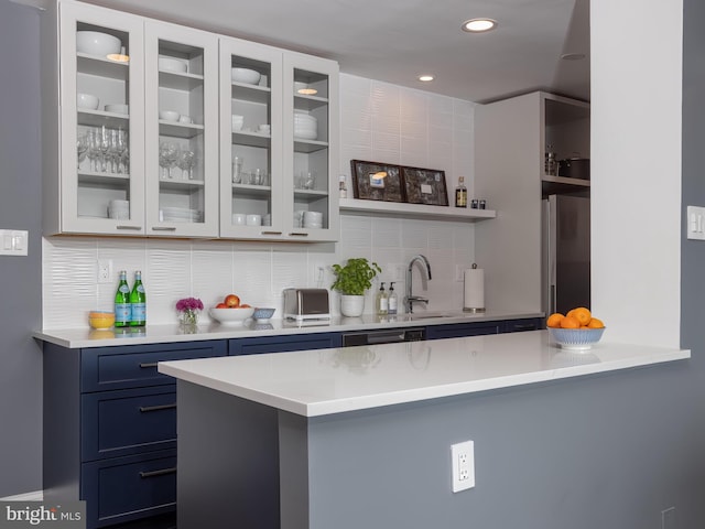 bar featuring decorative backsplash, sink, blue cabinetry, white cabinetry, and stainless steel fridge