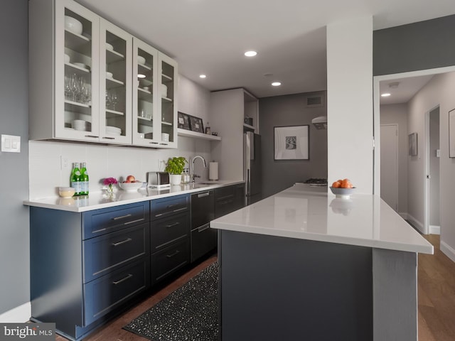 kitchen featuring stainless steel refrigerator, sink, backsplash, a center island, and dark hardwood / wood-style flooring