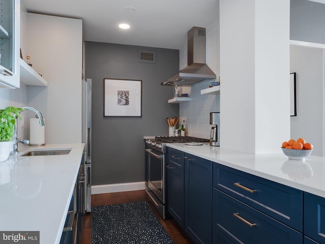 kitchen featuring blue cabinets, sink, wall chimney range hood, backsplash, and appliances with stainless steel finishes