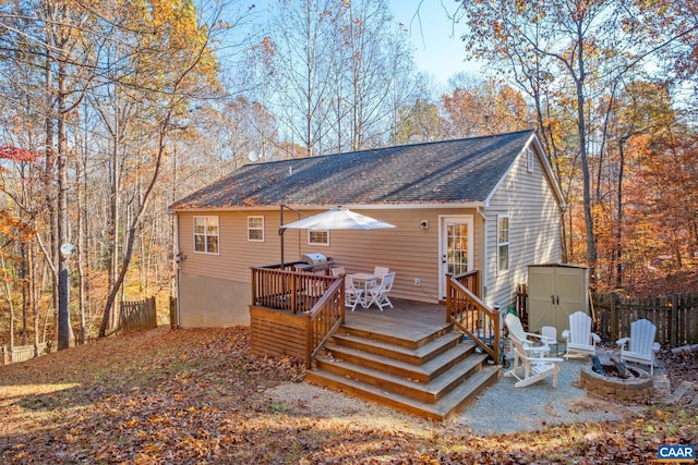 rear view of property featuring a fire pit, a storage unit, and a deck