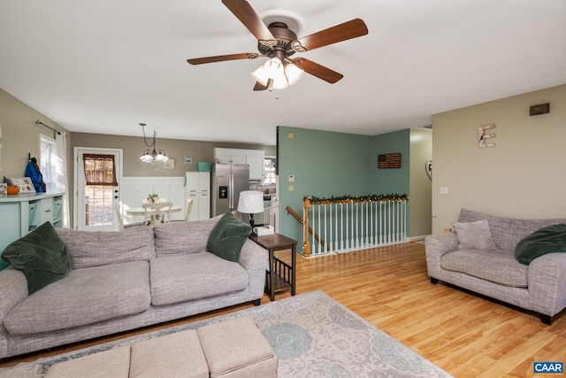 living room featuring wood-type flooring and ceiling fan with notable chandelier