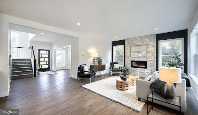 living room featuring a stone fireplace, plenty of natural light, and dark hardwood / wood-style floors