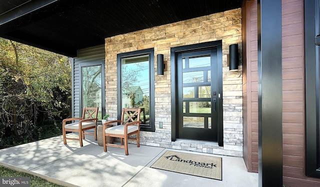 entrance to property featuring covered porch and stone siding