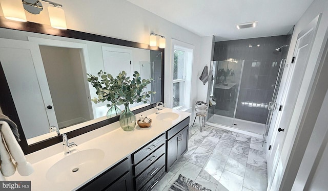 bathroom featuring a shower stall, marble finish flooring, and double vanity