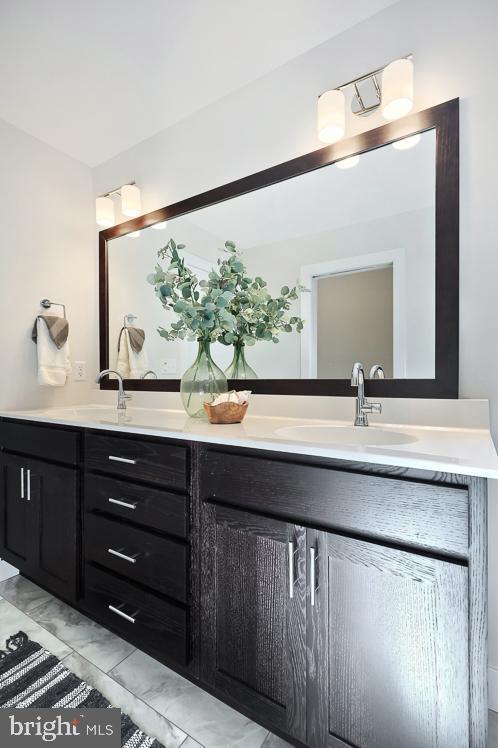 bathroom with double vanity and marble look tile flooring
