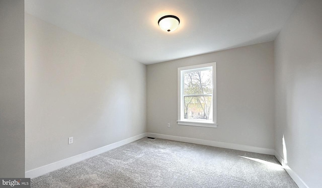 empty room featuring carpet and baseboards