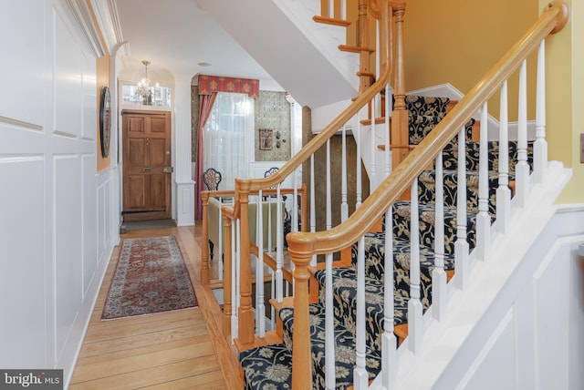 stairs with a chandelier and hardwood / wood-style flooring