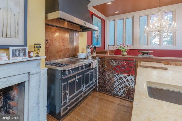 kitchen with tasteful backsplash, range hood, pendant lighting, range with two ovens, and wood-type flooring