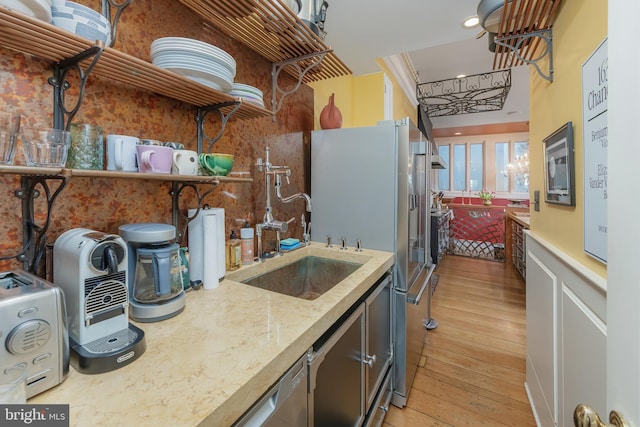 kitchen featuring stainless steel fridge, light hardwood / wood-style floors, light stone counters, and sink