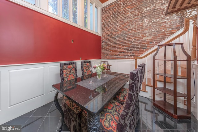 dining area featuring a towering ceiling, brick wall, and ornamental molding